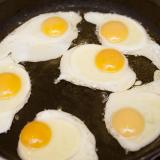 Six fried eggs in a pan with oil, for breakfast