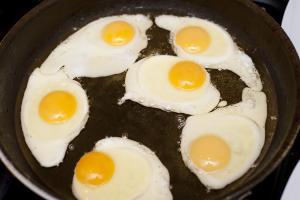 Six fried eggs in a pan with oil, for breakfast