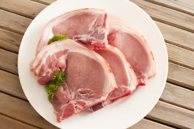 Four raw pork cutlets on a plate